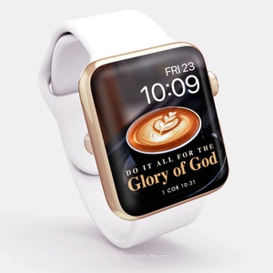 May include: A gold Apple Watch with a white band displays a black screen with a latte art coffee image and the text "DO IT ALL FOR THE GLORY OF GOD 1 COR 10:31". The time is 10:09 and the day is Friday, 23rd.
