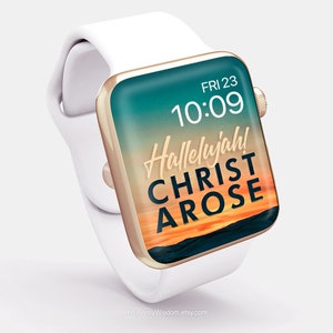 May include: A white Apple Watch with a gold band and a digital clock face that reads "FRI 23 10:09". The watch face also has a sunset background with the text "Hallelujah! CHRIST AROSE" in gold lettering.