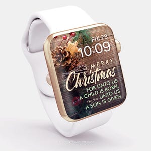 May include: A white Apple Watch with a gold band and a Christmas-themed watch face. The watch face features a wooden background with pine cones, berries, and greenery. The text on the watch face reads "Merry Christmas" and "For unto us a child is born, Isa 9:6 Unto us a son is given".