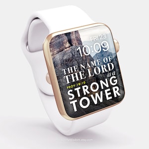 Op de afbeelding: Een witte Apple Watch met een gouden band en een digitaal klokje dat 10:09 aangeeft. De achtergrondafbeelding is een rotsachtig landschap met de tekst "THE NAME OF THE LORD is a STRONG TOWER" en de bijbelverwijzing "PROV 18:10".