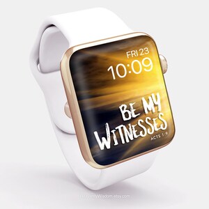 Op de afbeelding: Een witte Apple Watch met een gouden band en een zonsondergang-thema wijzerplaat. De wijzerplaat geeft de tijd 10:09 en de datum FRI 23 weer. De wijzerplaat bevat ook de tekst "BE MY WITNESSES" en "ACTS 1:9".