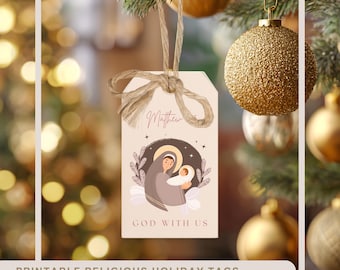 Può includere: Un'etichetta regalo rettangolare color beige con un'illustrazione marrone di una persona che tiene in braccio un bambino con un'aureola, il nome Matthew e il testo GOD WITH US. L'etichetta è appesa a uno spago di iuta annodato a fiocco.