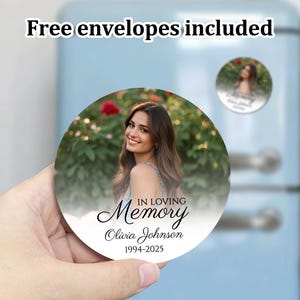 K&ouml;nnte beinhalten: Ein wei&szlig;er Gedenkmagnet mit einem Foto einer Frau in einer Blumenumgebung. Der Text lautet "In Loving Memory Olivia Johnson 1994-2025".