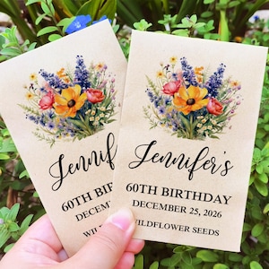 May include: Two brown paper seed packets with a floral design and text that reads "Jennifer's 60th Birthday December 25, 2026 Wildflower Seeds" and "Jennifer 60th Birthday December Wildflower Seeds".