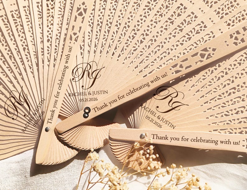 May include: Two wooden wedding fans with a lace design and the text "Thank you for celebrating with us!" and "Rachel & Justin 05.21.2026".