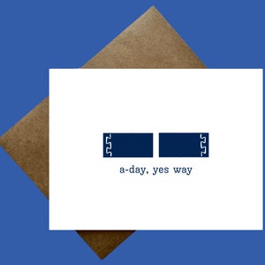 May include: A white card with two blue rectangles and the text "a-day, yes way" in black.