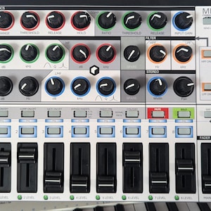 Puede incluir: Primer plano de un controlador de producción musical con perillas, deslizadores y botones. El controlador tiene un diseño blanco y gris con acentos azules. El texto "FX Sends", "Dynamics", "Comp", "Mix Channel", "EQ", "Filter", "Stereo", y "Fader" es visible en el controlador.