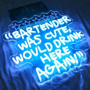 May include: Blue neon sign with white lettering that reads "The Bartender Was Cute! Would Drink Here Again!"