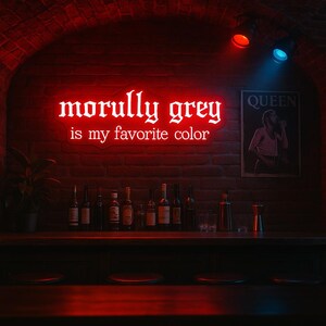 May include: A red neon sign displaying "morully grey is my favorite colour" hangs above a bar. The bar is stocked with bottles and glasses, and a Queen poster is on the brick wall. Red and blue spotlights illuminate the scene.