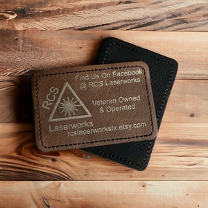 May include: A brown leather business card holder with the text "RCS Laserworks" and the words "Find Us On Facebook @ RCS Laserworks, Veteran Owned & Operated, rcslaserworkstx.etsy.com" engraved in silver.