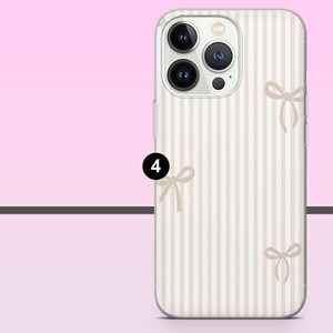 May include: A phone case with a vertical striped pattern in beige and white. The case features several small bow illustrations in a matching beige color. The phone case has a clear border and a camera module with three lenses.