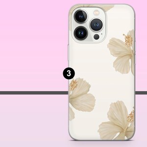 May include: A phone case with a cream-colored background and a floral design featuring beige hibiscus flowers. The case has a clear border and a camera cutout. The number "3" is in a black circle.