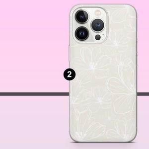 May include: A phone case with a floral design. The case is off-white with a pattern of white flowers. The phone case has a camera module with three lenses. The number 2 is printed in black on the side of the phone case.