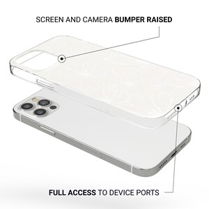 May include: Clear phone case with a white floral design, layered over a silver phone. The case has raised edges for screen and camera protection, with full access to device ports. The text on the image reads: "SCREEN AND CAMERA BUMPER RAISED" and "FULL ACCESS TO DEVICE PORTS."