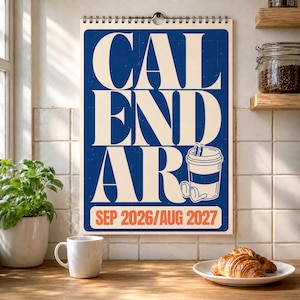 Può includere: Un calendario da parete con sfondo blu scuro e grande testo color crema che recita CALENDAR. È presente un'illustrazione di una tazza di caffè in stile cartone animato, con il testo SEP 2026/AUG 2027 stampato in arancione in basso.