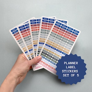 Puede incluir: Un conjunto de cinco pegatinas de etiquetas de planificador con etiquetas como "Metas", "Hábitos" y "Por hacer". Las etiquetas son de una variedad de colores, incluyendo azul, rojo y gris. El texto "Planner Label Stickers Set of 5" también es visible.