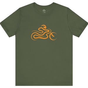 Könnte beinhalten: Ein grünes T-Shirt mit einer orangefarbenen Grafik eines Motorradfahrers.