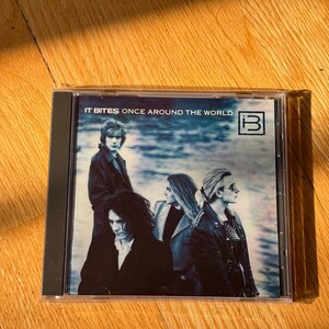 May include: A compact disc jewel case featuring the album Once Around the World by the band It Bites. The cover art displays a blue-toned photograph of four band members in dark clothing, with the text IT BITES ONCE AROUND THE WORLD and a logo.