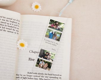 May include: A clear acrylic bookmark with three family photos and a light blue tassel. The bookmark has the text "Loving you is my favorite habit" and the name "Emily". The bookmark is placed in an open book with daisy decorations.