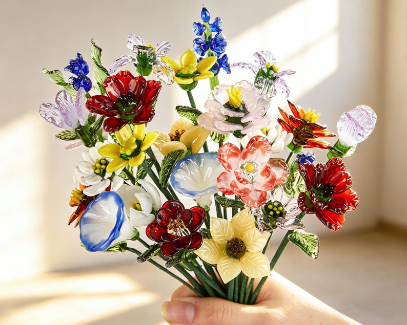 May include: A colorful bouquet of glass flowers in various shapes and colors, including red, yellow, blue, and white. The flowers are held together with green stems.