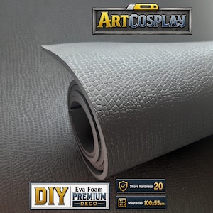 May include: A grey EVA foam sheet with a textured crocodile skin pattern, partially rolled. The image includes the text ARTCOSPLAY, DIY PREMIUM DECO, Shore hardness 20, and sheet sizes 100x55cm. The material has a matte finish and uniform color.