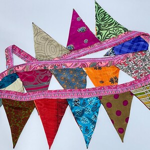 May include: A colourful fabric bunting with a pink trim and a variety of patterns, including paisley, floral, and geometric designs.