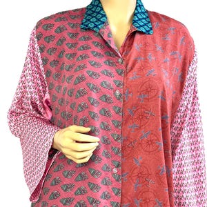 Könnte beinhalten: Ein Hemd mit Knopfleiste und Patchwork-Design. Das Hemd hat einen türkisfarbenen Kragen, einen rosa Muscheldruck, einen roten Flugzeugdruck und rosa Blumenärmel. Das Hemd hat lange Ärmel und ist aus leichtem Stoff gefertigt.