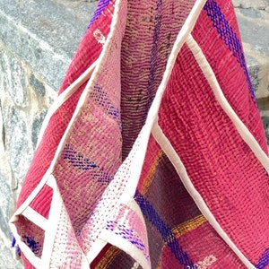 K&ouml;nnte beinhalten: Eine rosa und rote Kantha-Steppdecke-Tasche mit wei&szlig;em Besatz und blauen Stickereien. Die Tasche ist in der Mitte gefaltet und das Innere ist sichtbar.