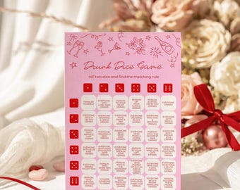 May include: Pink "Drunk Dice Game" card with dice and drinking rules. The card has a decorative floral and champagne bottle design. A red ribbon and heart-shaped decorations are in the foreground.