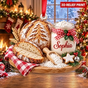 Può includere: Un addobbo natalizio rotondo con una stampa in rilievo 3D raffigurante una pagnotta di pane a lievitazione naturale con un motivo ad albero, un barattolo di farina etichettato Sophia con nastro a quadretti rossi, un cucchiaio di legno e un biscotto a stella.