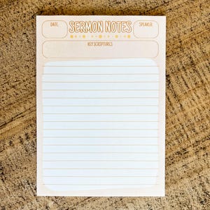 May include: A light pink Sermon Notes notepad with lined pages. The top section includes spaces for the date, speaker, and key scriptures. The words "Sermon Notes" are in a decorative font.