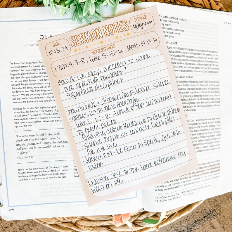 May include: A light pink sermon notes card with handwritten notes, resting on an open Bible. The card has the title "Sermon Notes" and key scripture references. The notes are in black ink.