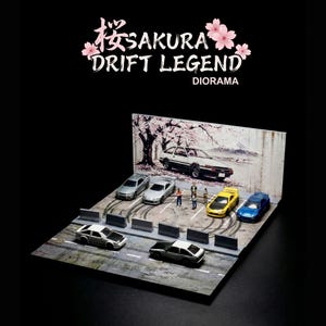 Pode incluir: Um diorama com carros em miniatura em uma cena de rua com marcas de pneus. O diorama inclui um cenário com uma cerejeira em flor e o texto "SAKURA DRIFT LEGEND DIORAMA". Vários carros estão estacionados na rua.