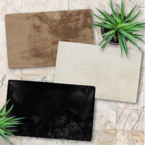 May include: Three rectangular rugs in shades of brown, cream, and black are displayed on a marble tile surface. A potted green plant is positioned near the rugs. The rugs have a soft, textured appearance.