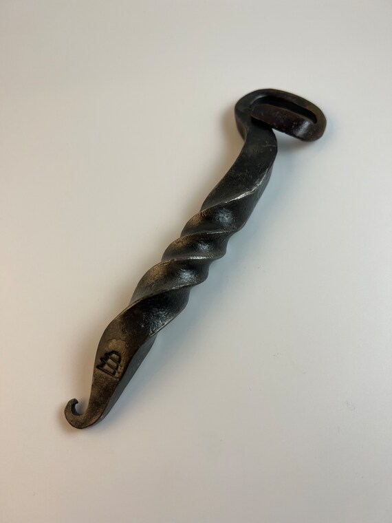 Hand-forged blacksmithing with swirling decorative handle details — this is a functional art piece that doubles as a conversation-starting bar tool.
