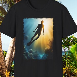 May include: Black t-shirt with a graphic print of a diver silhouetted against a sunbeam underwater. The diver is wearing a wetsuit and flippers. The background is a blue and green coral reef.