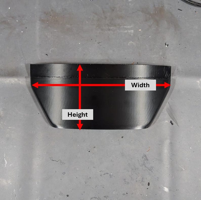 May include: A black, trapezoidal-shaped object with labeled dimensions. The image shows the height and width of the object. The object appears to be made of a solid material and is set against a gray surface.