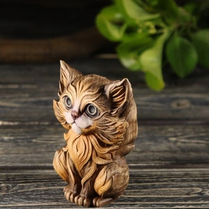 Pu&ograve; includere: Una statuetta di legno di un gatto marrone e bianco con grandi occhi. Il gatto &egrave; seduto con la testa inclinata di lato e la coda arrotolata attorno al suo corpo.