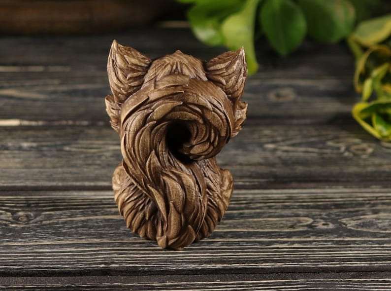 Pu&ograve; includere: Una scultura in legno di una volpe con la coda arrotolata attorno al suo corpo. La scultura &egrave; dettagliata e realistica, con una finitura in legno marrone.