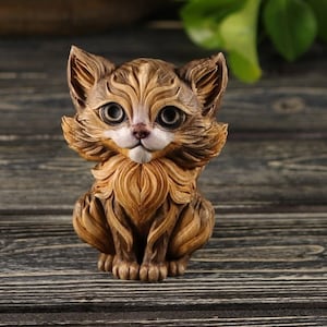 Pu&ograve; includere: Una piccola statuetta di legno intagliata in modo intricato che rappresenta un gatto marrone e bianco con grandi occhi espressivi. Il gatto &egrave; seduto con le zampe ripiegate sotto di lui e la coda arrotolata attorno al suo corpo.