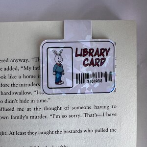 Puede incluir: Un marcap&aacute;ginas blanco con un conejito de dibujos animados y el texto "LIBRARY CARD" con un c&oacute;digo de barras que dice "2101908".
