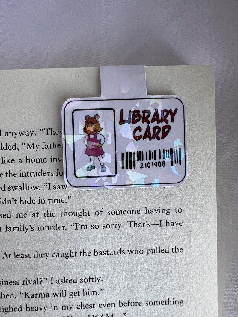 Puede incluir: Una tarjeta de biblioteca rosa y blanca con un c&oacute;digo de barras y el texto "LIBRARY CARD" en negro. Una imagen de dibujos animados de una ni&ntilde;a con cabello casta&ntilde;o y un vestido rosa est&aacute; en la esquina superior izquierda.