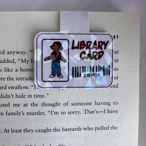 Puede incluir: Una tarjeta de biblioteca colorida con una ilustraci&oacute;n de dibujos animados de una persona. La tarjeta tiene el texto "LIBRARY CARD" y un c&oacute;digo de barras con el n&uacute;mero "2101908".
