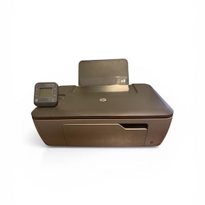 May include: A bronze-colored HP Deskjet 3050A all-in-one printer. The printer has a small LCD screen and a paper output tray. The HP logo is visible on the top. The printer is on a white background.