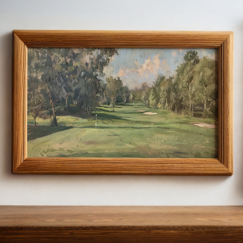 May include: A framed oil painting depicting a golf course with green grass, trees, and a blue sky with white clouds. The painting is in a wooden frame.