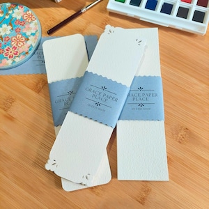 May include: Three white bookmark cards with scalloped edges and a blue banner that reads "Grace Paper Place, An Etsy Shop".