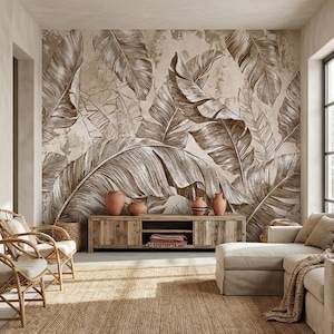 Könnte beinhalten: Wohnzimmer mit großem Wandbild aus braunen und weißen Bananenblättern. Unter dem Wandbild befindet sich ein TV-Schrank aus Holz mit Terrakotta-Vasen. Korbstühle und ein beiges Ecksofa ergänzen den Raum, zusammen mit einem gewebten Teppich.