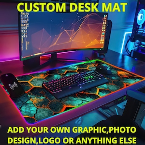 May include: A custom desk mat with a colourful, abstract design featuring a honeycomb pattern. The mat has a black, rainbow-coloured border. The text "CUSTOM DESK MAT" is at the top of the image. The text "ADD YOUR OWN GRAPHIC, PHOTO DESIGN, LOGO OR ANYTHING ELSE" is at the bottom of the image.