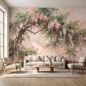 Op de afbeelding: Een woonkamer met een muurschildering van een bloeiende blauweregenboom in roze, paarse en groene tinten. De kamer is ingericht met een beige bank, fauteuils, een salontafel en een houten vloer, wat een serene sfeer creëert.