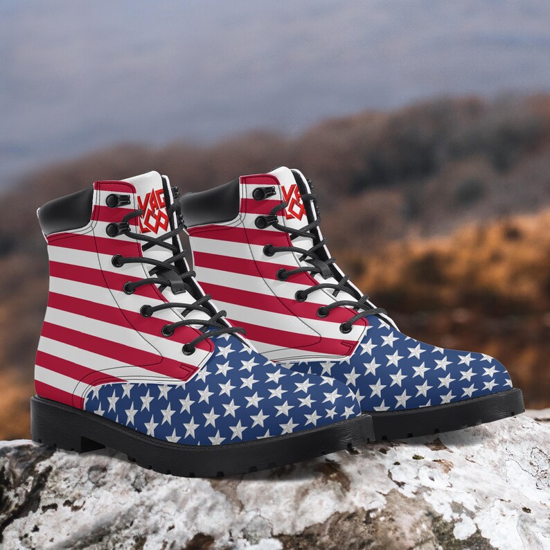 May include: A pair of combat boots featuring the American flag design. The boots have a red and white striped upper, a blue star-patterned toe, black laces, and a black sole. The boots have the text "VAG XX" on the side.